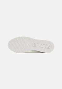 Semelle en caoutchouc blanc de la sneaker Levi's, avec un motif texturé et le logo "Levi's" embouti en gris près du talon.