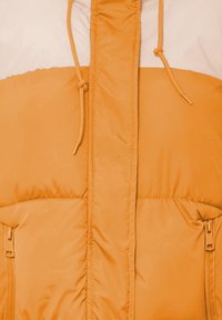 Orange puffjakke med en hvid øverste del, der har en fuld frontlynlås, justerbar snørehætte og sidelommer. Glat tekstur.