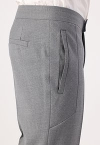 Graue maßgeschneiderte Hose mit glatter Textur, schrägen Seitentaschen und flachem Bund. Der Stoff hat ein dezentes gewebtes Muster.