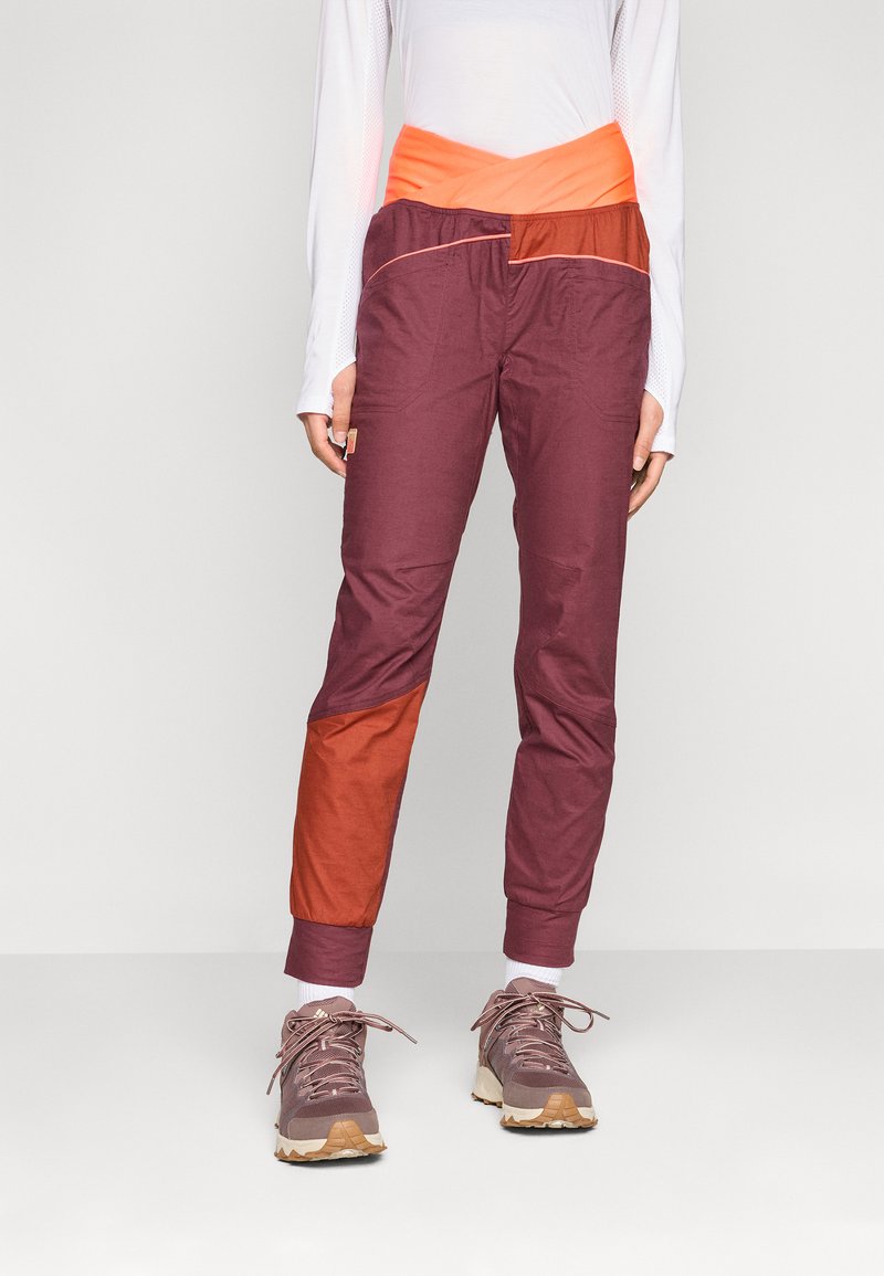 Bordeaux und rostfarbene, farblich abgesetzte Hosen mit einem orangen Bund, aus elastischem Material und mit schmal zulaufendem Bein, gestaltet für Komfort und Bewegung.