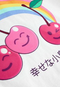 Graafika kujutab kolmekesi roosasid kirsse naeratavate nägudega, valgel taustal ja üleval vikerkaar, allosas tumevioletse tekstiga.