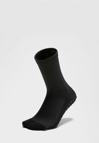 Calza atletica nera con un design a coste, lunghezza fino al polpaccio e grip testurizzato sulla suola. Realizzata in materiale elastico e comodo.