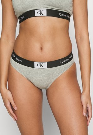 Boxer in cotone grigio con una cintura nera decorata dal marchio e logo "Calvin Klein" in bianco. Tessuto morbido, design a vita bassa.