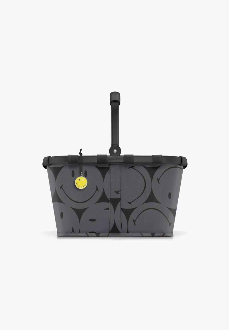 Gray shopping basket with black smiley face pattern, black handle, and a yellow smiley charm attached. Made of durable fabric.