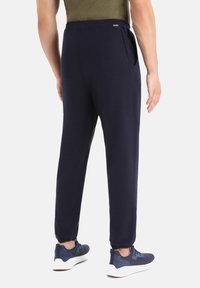 Marina joggerbyxor i mjukt tyg, med elastisk midja, sidofickor och samlade ärmslut, kombinerat med marina sportskor.