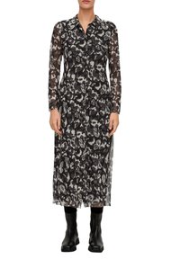 Schwarzes und weißes durchscheinendes Kleid mit langen Ärmeln, Knopfleiste vorne und Leopardenmuster. Getragen mit schwarzen Knöchelstiefeln.