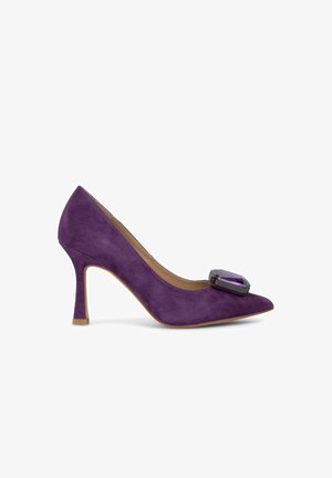 Lila Wildleder-Pumps mit hohem Absatz und spitzer Zehenpartie, die auf dem Blatt einen auffälligen Schmuckakzent in lila und grauen Farbtönen aufweist.