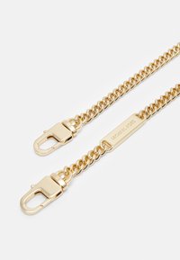 Guld kæde tilbehør med sammenkoblede led, med clipslås i begge ender og et mærkat graveret med brandnavnet.