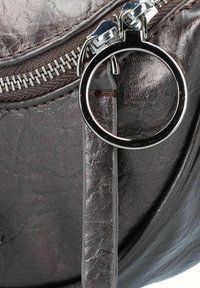 Borsa rotonda in pelle marrone scuro con zip argentata lucida, un accent hardware circolare e superficie texturizzata con leggere pieghe.