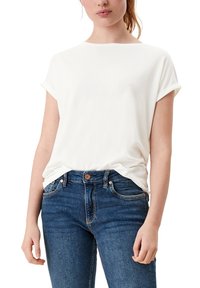 Bílé bavlněné tričko s krátkými vyhrnutými rukávy, volný střih, kulatý výstřih, zobrazené ve spojení s tmavě modrými džínami.