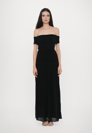 Zwarte off-shoulder jurk met geplooide textuur bij de buste, vloeiende maxi lengte en een gladde afwerking. Model staat tegen een witte achtergrond.