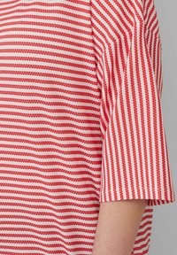 Rood en wit gestreept T-shirt met een loose fit, korte mouwen en een gestructureerde stof. Verticale strepen creëren een golvend patroon.