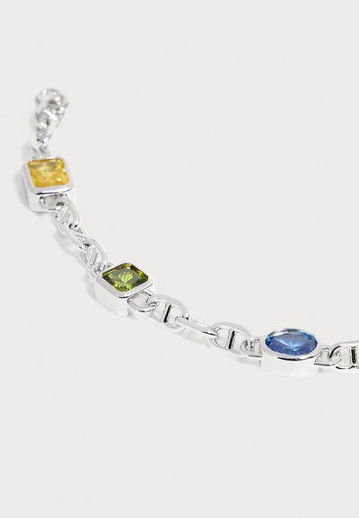Bracelet chaîne en argent avec des pierres carrées jaunes et vertes et une pierre ovale bleue sertie dans des montures métalliques.