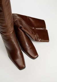 Bottes basses en cuir marron à texture lisse, avec un bout carré et une tige pliée et lâche.