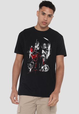 Black cotton t-shirt featuring a graphic print of a character in red, with a stylized background and logo detail in white. Short sleeves.