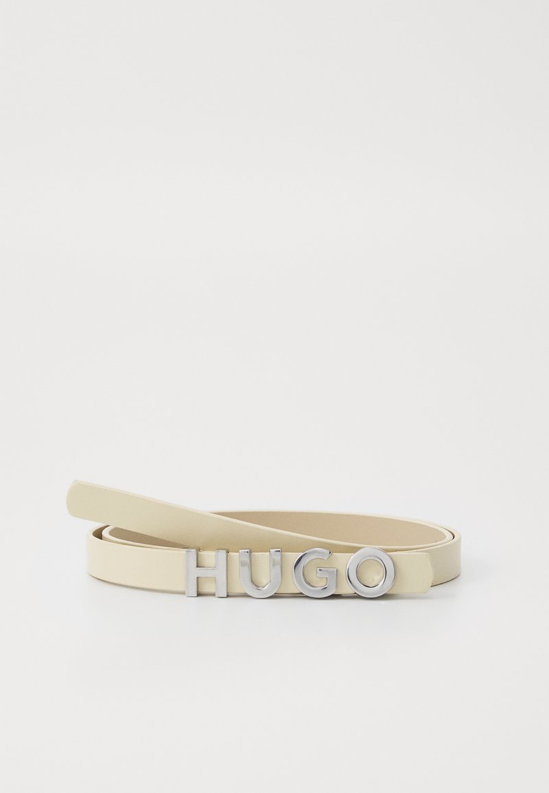 Beige læderbælte med et slankt design, prydet med et sølvfarvet "HUGO" logo som en fremtrædende detalje foran. Glat tekstur og minimal hardware.