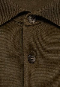 Polo de punto marrón con un acabado texturizado, que presenta un cuello y una botonera de dos botones. Los botones son oscuros y tienen cuatro orificios cada uno.