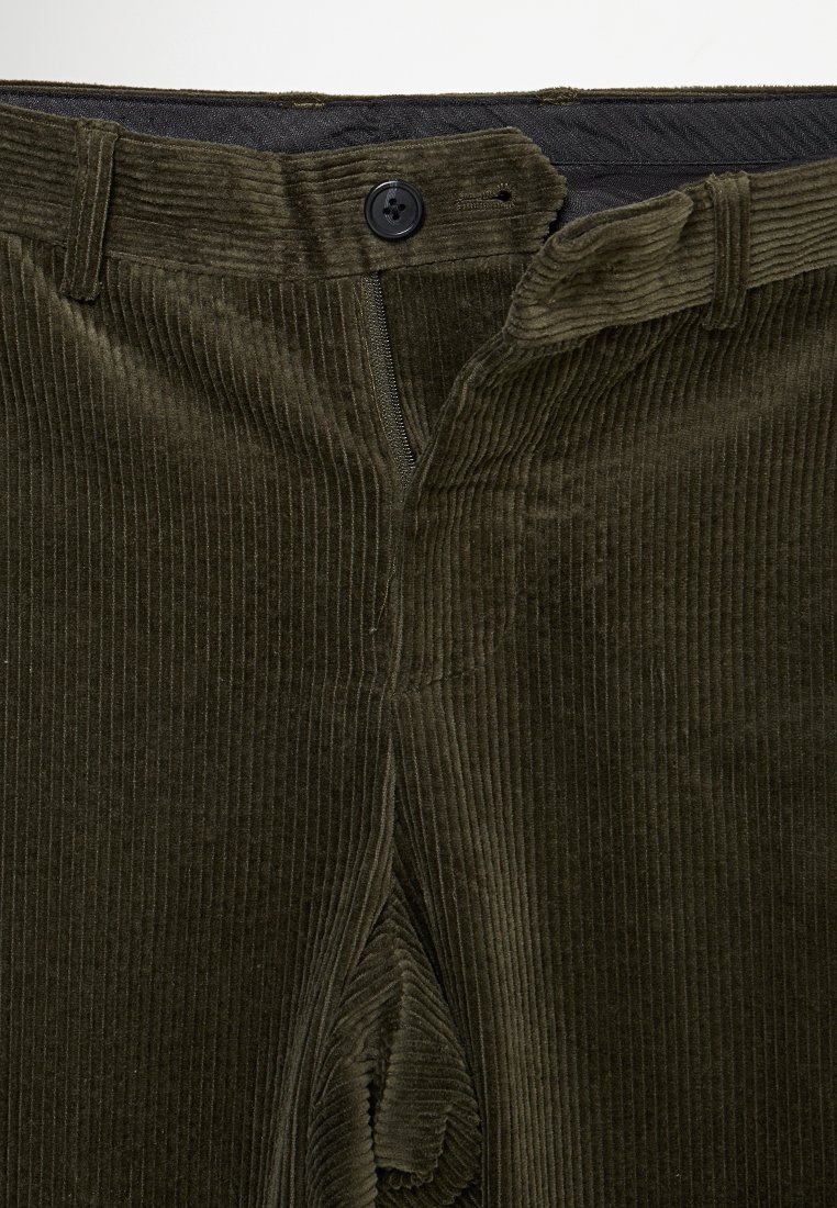 Olivgrüne Cordhosen mit vertikaler Rippenstruktur, Knopfverschluss und Seitentaschen. Der Stoff hat eine weiche, strukturierte Oberfläche.