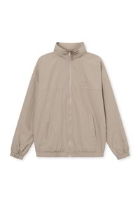 Giacca zip-up beige chiaro con colletto alto, polsini elasticizzati, tasche frontali e un logo discreto sul petto. Tessuto testurizzato.