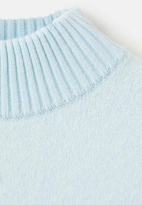 Podrobnost svetlomodrega puloverja z rebrastim vratnim delom, mehko teksturo in gladkim telesom ter lahkim pletenim zaključkom tkanine.