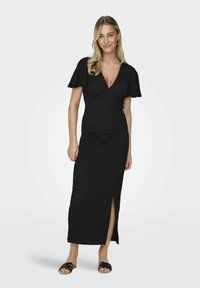 Vestido negro ajustado con tejido texturizado, escote en V y mangas con vuelo. Presenta una abertura lateral y un diseño largo y fluido.