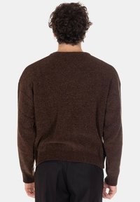 Maglione marrone con trama, scollo rotondo, spalle scese e polsini e orlo a costine. Design semplice, silhouette aderente.