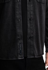 Zwarte denim overhemd met een knoopsluiting aan de voorkant en patch pockets. Het beschikt over een gestructureerde stof, een standaard kraag en een merketiket aan de zoom.