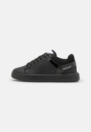 Zapatilla baja negra con cierre de cordones, detalle de charol y la marca "Trussardi" en la correa del talón y la suela.