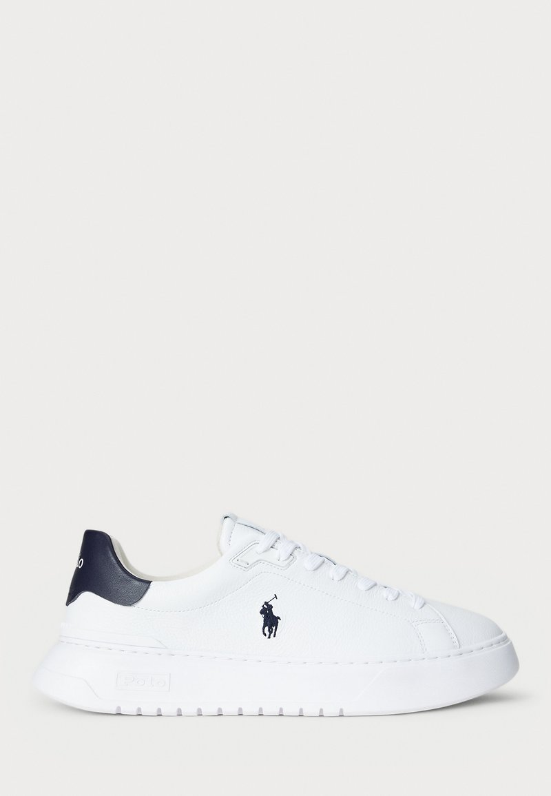 Hvitt skinnsneaker med teksturert overflate, marineblå hælaksent og en liten marineblå logo på siden. Tykk hvit såle med riflet bunn.