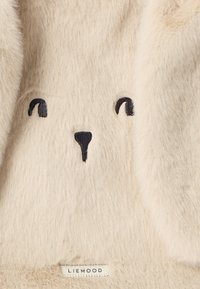 Material moale de culoare crem cu broderie în formă de nas și ochi de urs negru, având un mic etichetă a mărcii "LIEWOOD" în partea de jos.