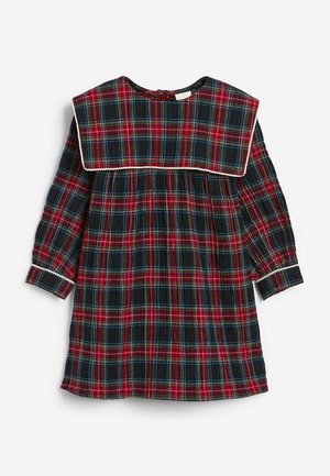 Robe à carreaux rouges et noirs avec des accents bleus, un grand col carré, des manches longues et un détail de taille froncée. Présente des bordures blanches.