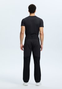 Zwarte sportieve shirt en broek met een strakke pasvorm. De broek heeft een gladde textuur, een verstelbare tailleband en een contrasterend paneel op de onderbenen.