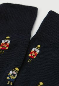 Calze blu navy con trama a coste che presentano motivi colorati di schiaccianoci in rosso, giallo e blu. Adatte per un abbigliamento casual o festivo.