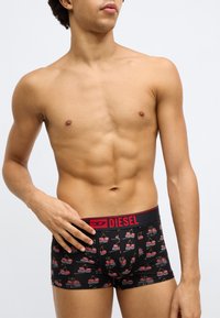 Fekete boxeralsó piros derékpánttal, amelyen "DIESEL" logó és cseresznyeminta található. Puha, rugalmas anyagból készült.
