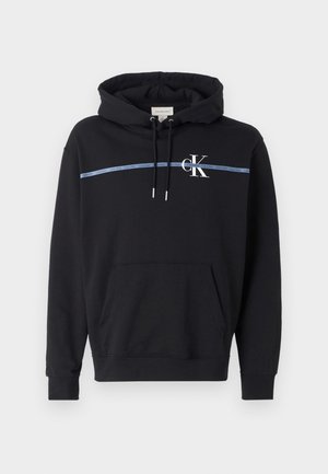Schwarzer Pullover-Hoodie mit verstellbaren Kordeln, Kängurutasche vorne, blauem Streifen mit wiederholtem „Calvin Klein“-Text und weißem „cK“-Logo auf der Brust.