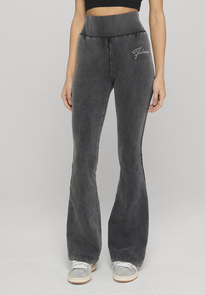 Pantalones acampanados en gris oscuro, hechos de tela suave. Presentan una cintura alta acanalada y un pequeño logo de cristal en la cadera izquierda.