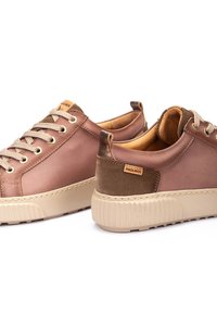 Zapatillas de cuero marrón con acentos texturizados, suela de goma beige y cordones beige. Presenta el logotipo de Pikolinos en el talón.