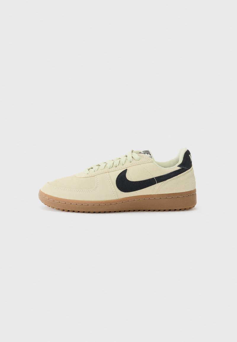Lysegule ruskind sneakers med sort swoosh-logo, flade snørebånd og brun gummisål. Klassisk low-top design. Struktureret materiale.