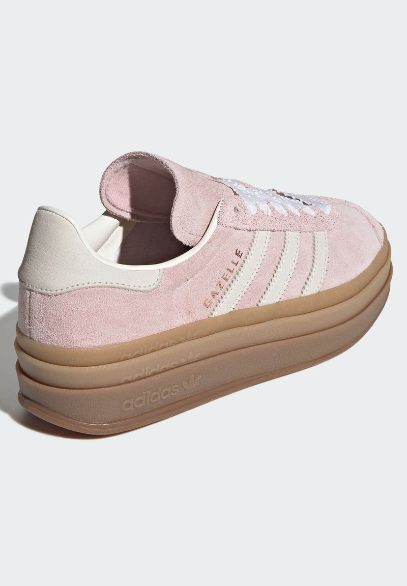 Roze suède sneaker met een witte leren hiel en drie witte strepen. Voorzien van een dikke, doorschijnende gumzool en een vetersluiting aan de voorkant.