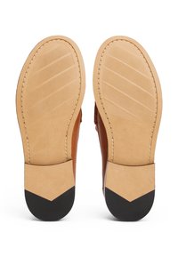Brown leather shoe soles with a light tan base and black heel accents. The soles feature horizontal grooves for traction and a stitched edge.