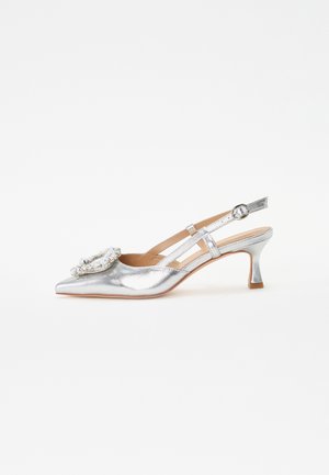 Zapato de slingback metálico plateado con punta afilada, que presenta una decoración floral y un tacón bajo, en bloque. Correas delgadas añaden detalle.