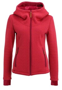 Veste rouge à motifs zippée avec col montant, deux poches avant zippées et manches longues avec poignets intérieurs prolongés.