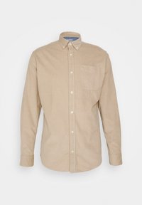 Camisa beige de manga larga fabricada con tela texturizada, con cuello tipo botón, bolsillo frontal y botones blancos.