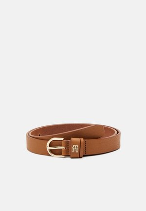Ceinture en cuir marron enroulée avec une boucle métallique dorée et un petit emblème « H » sur la boucle de ceinture sur un fond uni.