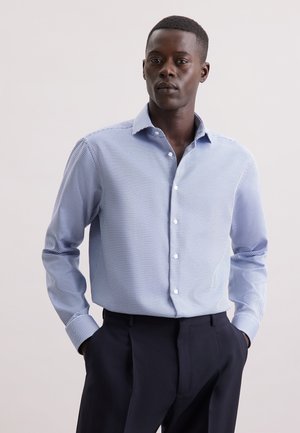 Niebieska i biała koszula w kratę z zapięciem na guziki, z pointed collar, długimi rękawami i slim fit. Materiał wygląda na lekki o gładkiej teksturze.