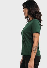 Grünes Kurzarmhemd aus strukturiertem Stoff, mit lockerer Passform und dezenten Nähdetails, kombiniert mit dunklen Hosen.