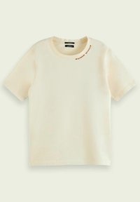 Krémové tričko s krátkým rukávem z bavlny, kulatý výstřih a malý hnědý nápis "Maison Scotch" poblíž výstřihu na levé straně.
