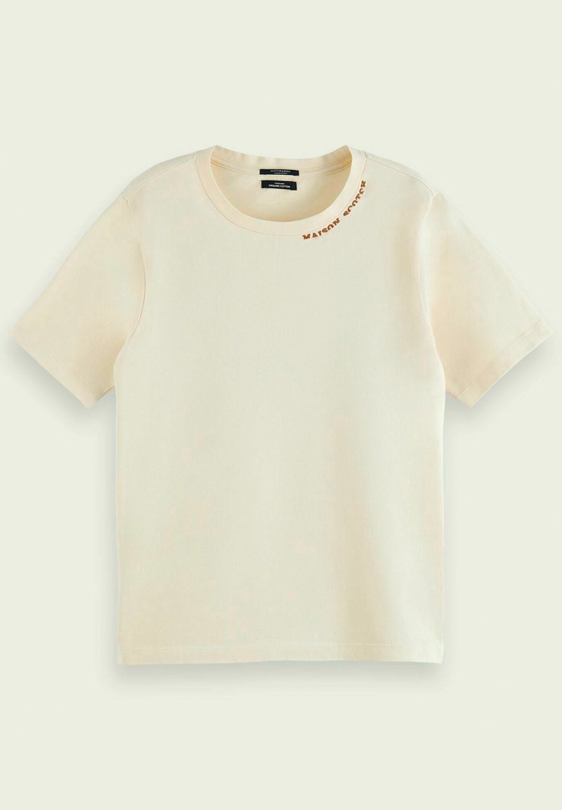 Krémové tričko s krátkým rukávem z bavlny, kulatý výstřih a malý hnědý nápis "Maison Scotch" poblíž výstřihu na levé straně.
