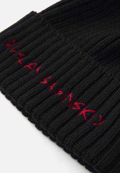 Zwarte geribbelde gebreide beanie met rode geborduurde tekst. Heeft een dikke, gestructureerde patroon en een aansluitende pasvorm. Geen zichtbare logo's of extra details.