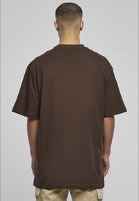 Smeđa oversized majica s kratkim rukavima, okruglog izreza, izrađena od mekanog pamučnog materijala, s jednostavnim dizajnom bez uzoraka ili naglasaka.